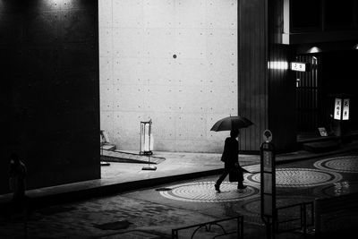 Rear view of person walking on wet street during rainy season