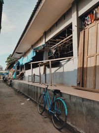 Bicycle by building in city against sky