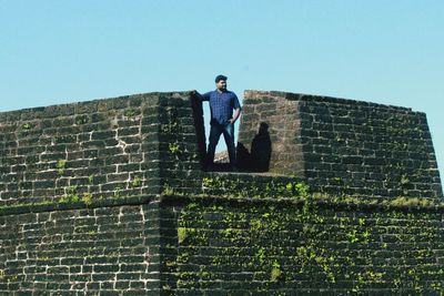 Low angle view of man standing against brick wall