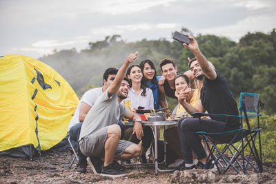 Group of people using phone while sitting on land