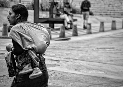 Rear view of woman carrying child while walking outdoors