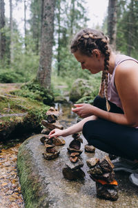 Side view of woman sitting on land in forest