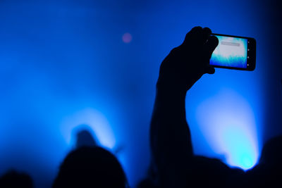 Silhouette of man photographing music concert