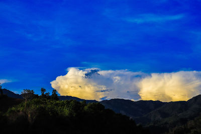 Low angle view of silhouette mountain against blue sky