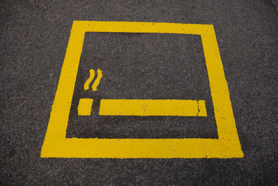 Close-up of yellow arrow sign on road