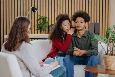 Portrait of friends sitting on sofa at home