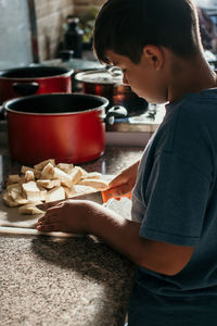 Side view of boy holding ice cream in kitchen