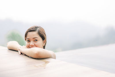 Portrait of young woman sitting on bed at home