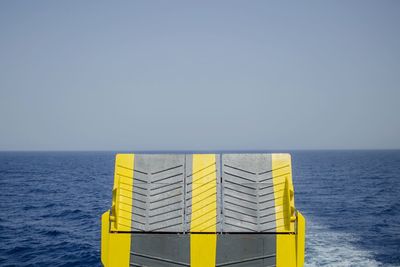 Cropped image of ferry ramp on sea against clear sky