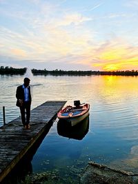 Man standing on lake against sky during sunset