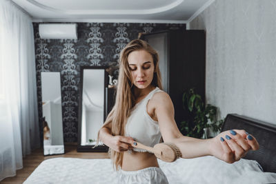 Young woman using hairbrush at home