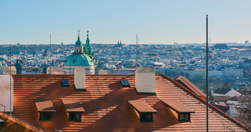 Cityscape of prague with cathedral of st. nicholas at sunny day, with red roof in the foreground.