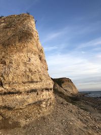 Rock formation by sea against sky