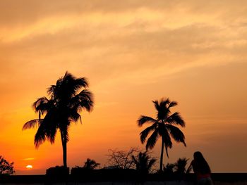 Silhouette palm trees against sky at sunset