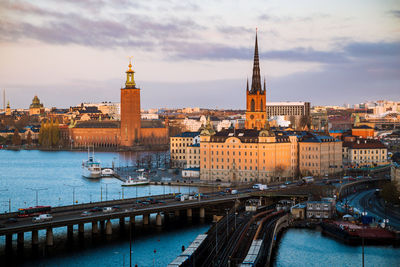 Bridge over river by buildings in city against sky