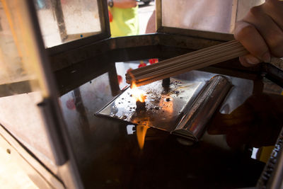 Cropped hand of person burning incense