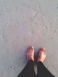 Low section of woman standing on wet sand