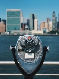 Close-up of coin-operated binoculars against cityscape