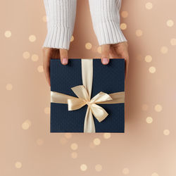 Christmas background. female hands in white sweater with natural manicure hold blue gift box