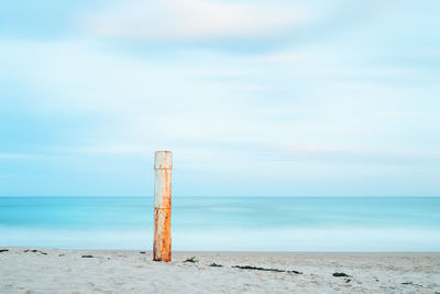 Wooden posts on beach against sky