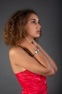 Portrait of young woman standing against gray background