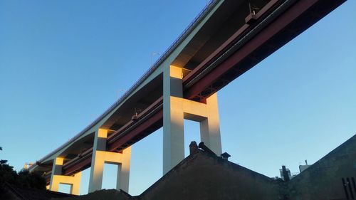 Low angle view of yellow bridge against clear blue sky