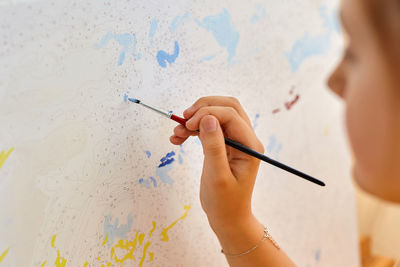 Cropped hand of girl painting on paper