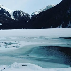 Scenic view of frozen lake by mountains against sky