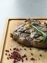 Close-up of fresh grilled beef steak on wooden cutting board with spices