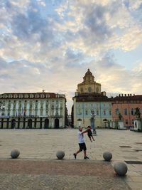 Man playing soccer ball against building in city against sky