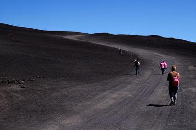 Rear view of people hiking at mount etna