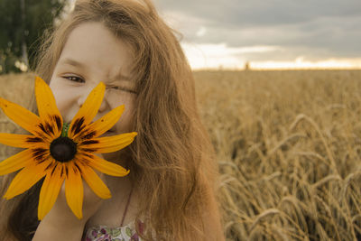 Portrait of woman with yellow flowers on field