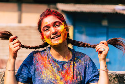 Portrait of smiling young woman holding multi colored umbrellas