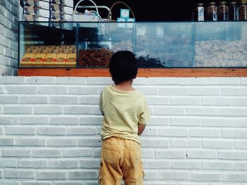 Rear view of boy looking at food in display in store