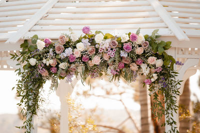 Beautiful white wedding gazebo with floral arrangements - pink roses and eucalyptus leaves