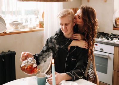 A couple in love have breakfast and drink tea in a decorated eco-style kitchen in a country house