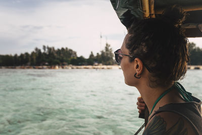 Side view of young woman wearing sunglasses against sea