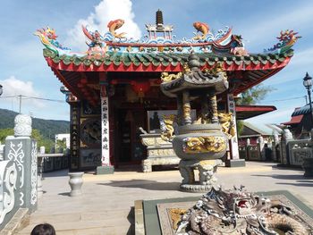 Statue in temple against cloudy sky