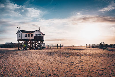 Lifeguard hut on beach by sea against sky during sunset