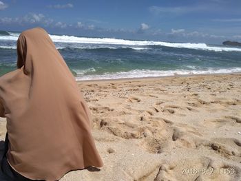 Midsection of man on beach against sky