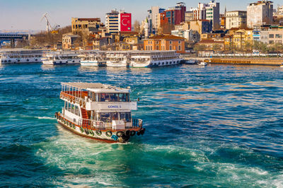 Ferry boat in sea against buildings in city