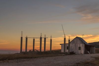 Buildings on field against sky during sunset