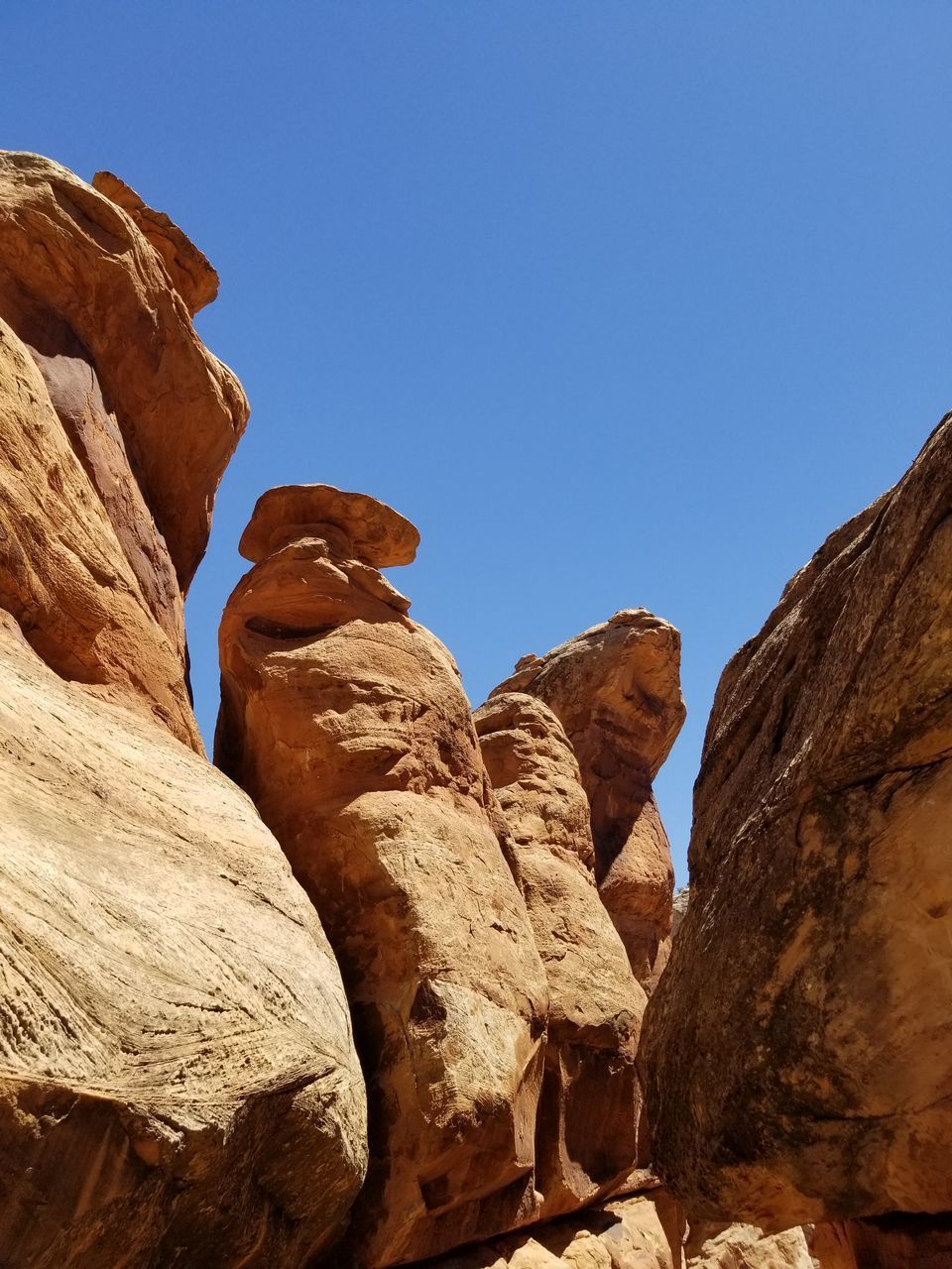 LOW ANGLE VIEW OF ROCK FORMATIONS AGAINST CLEAR BLUE SKY