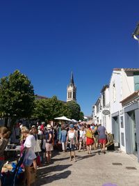 People at temple against clear blue sky