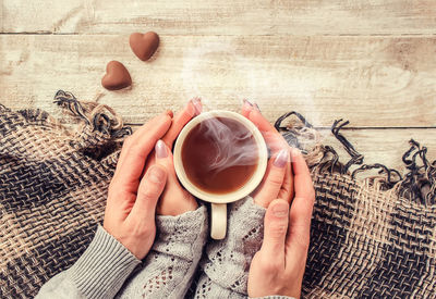 Cropped hand of woman holding coffee on table