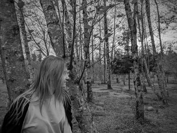 Woman standing by trees in forest