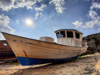 Abandoned boat moored on beach against sky