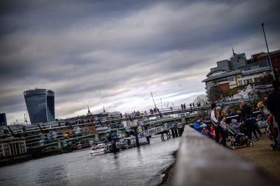 View of city at waterfront against cloudy sky