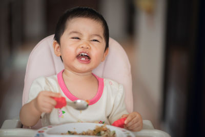 Cute baby girl eating food at home