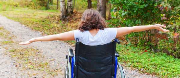 Rear view of woman sitting on wheelchair outdoors